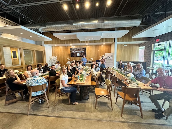 Image of group of business owners at a networking group called, The Net in The Woodlands Texas. Rob is presenting about AI at the restaurant Local Table in one of their meeting rooms in front of a large TV with the name "Ready Stacks" on the screen.